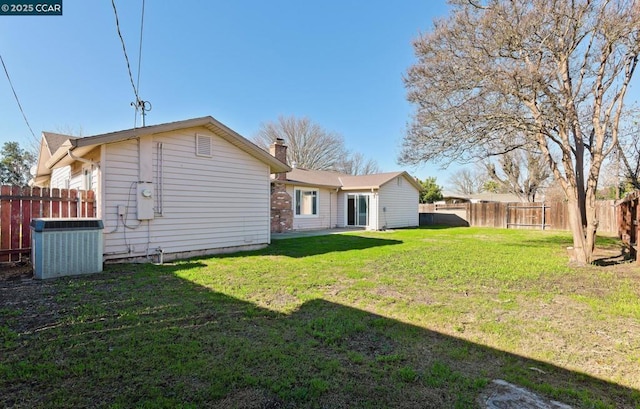 back of house with a yard and central air condition unit