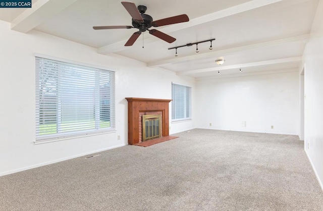 unfurnished living room with ceiling fan, carpet floors, a brick fireplace, beam ceiling, and rail lighting