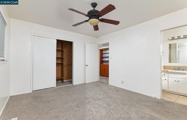 unfurnished bedroom with light carpet, ceiling fan, connected bathroom, and sink