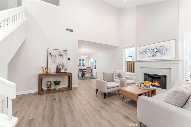 living room featuring a chandelier, a high ceiling, and light wood-type flooring