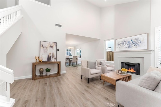 living room with light hardwood / wood-style floors, a high ceiling, and a notable chandelier