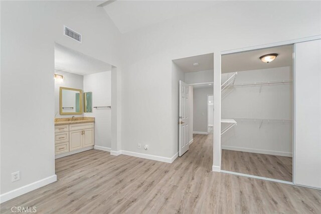 unfurnished bedroom featuring a closet, ensuite bath, sink, and light hardwood / wood-style flooring