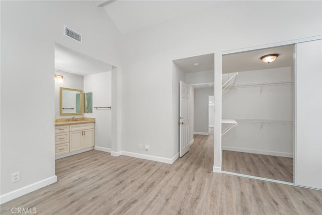 unfurnished bedroom with sink, light wood-type flooring, ensuite bath, and a closet