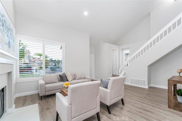 living room with high vaulted ceiling and light hardwood / wood-style flooring