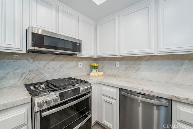 kitchen featuring appliances with stainless steel finishes, decorative backsplash, light stone counters, and white cabinets