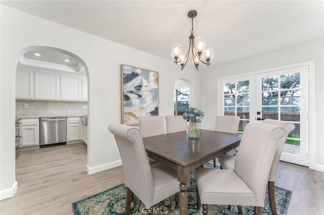 dining space with french doors, a notable chandelier, and light hardwood / wood-style flooring