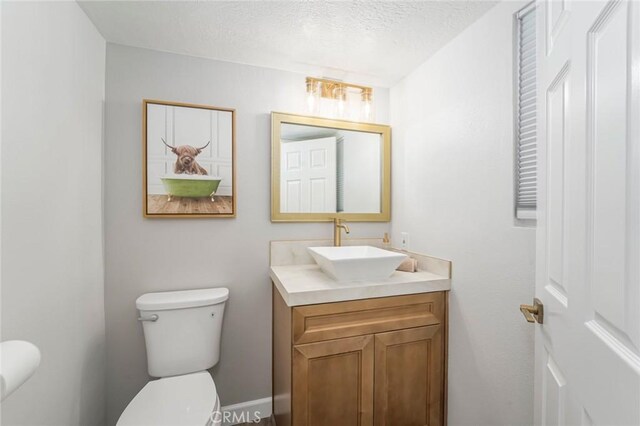 bathroom featuring vanity, a textured ceiling, and toilet