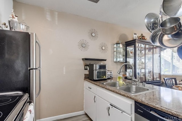 kitchen featuring baseboards, white cabinets, appliances with stainless steel finishes, light wood-type flooring, and a sink