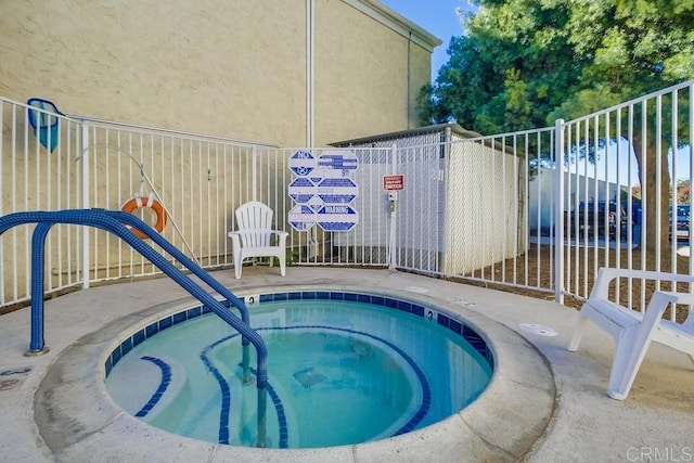 view of swimming pool featuring fence and a hot tub