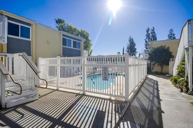 community pool with a patio and fence