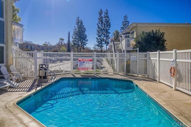 community pool with a patio area and fence