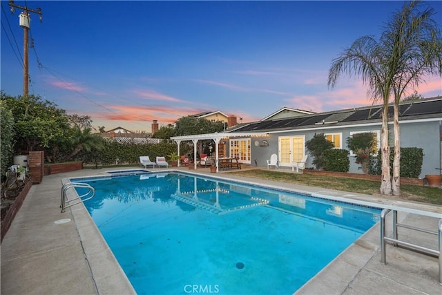 pool at dusk with a patio area and a pergola