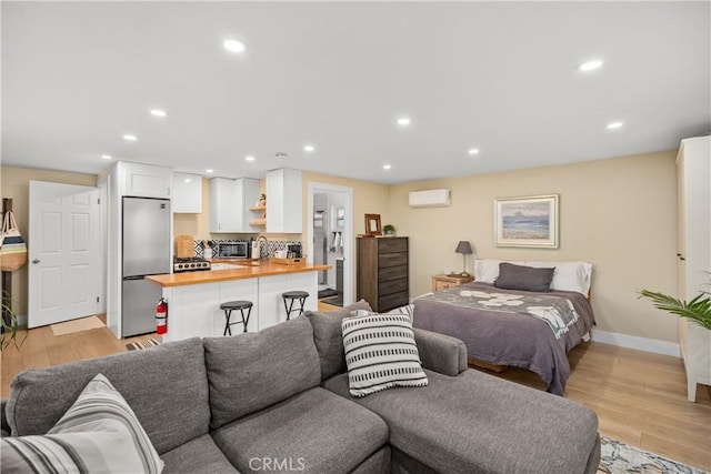 bedroom featuring light wood-type flooring, built in refrigerator, and a wall mounted air conditioner