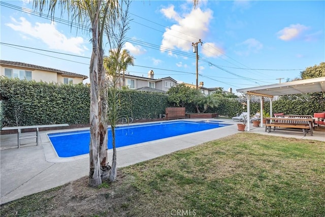 view of pool featuring a yard, a diving board, and a patio