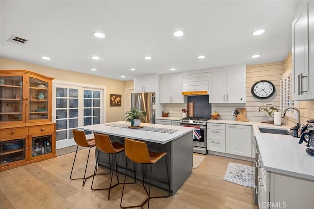 kitchen with a center island, white cabinetry, light hardwood / wood-style flooring, a kitchen breakfast bar, and stainless steel appliances