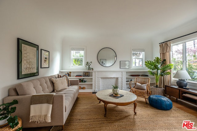 living room with a brick fireplace and hardwood / wood-style floors