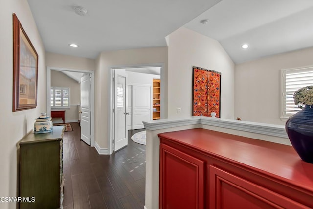 corridor with vaulted ceiling, plenty of natural light, and dark hardwood / wood-style flooring