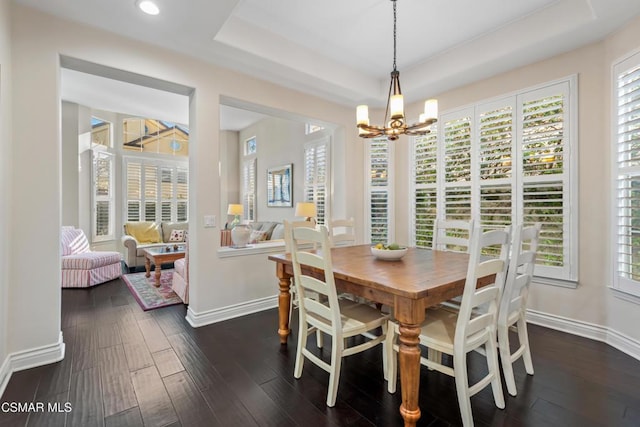 dining area featuring a tray ceiling, dark hardwood / wood-style flooring, and a notable chandelier