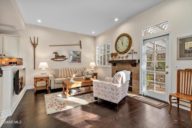 living room with a tile fireplace and dark hardwood / wood-style floors