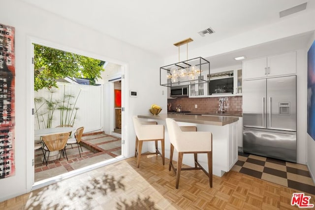 kitchen featuring hanging light fixtures, kitchen peninsula, appliances with stainless steel finishes, and white cabinetry