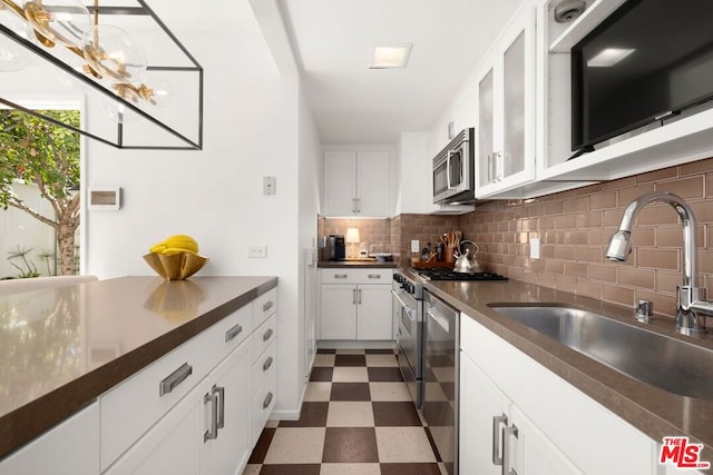 kitchen with dishwashing machine, white cabinets, tasteful backsplash, and sink