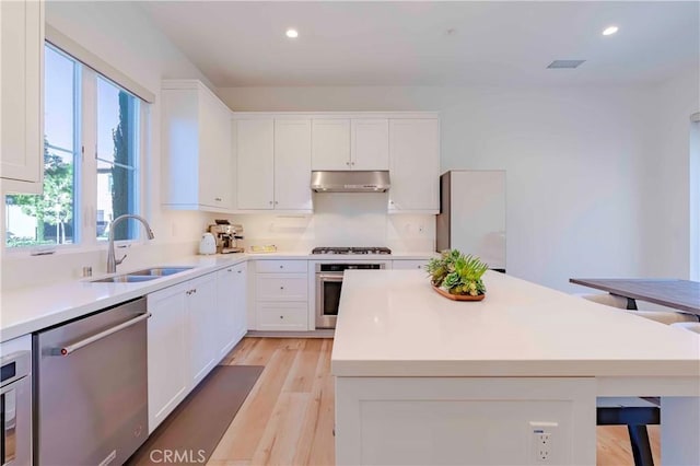 kitchen featuring stainless steel appliances, a center island, white cabinets, and sink