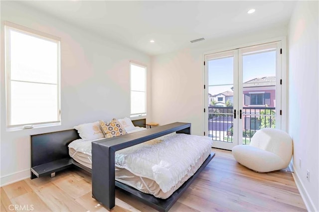 bedroom featuring access to exterior, french doors, multiple windows, and light hardwood / wood-style flooring