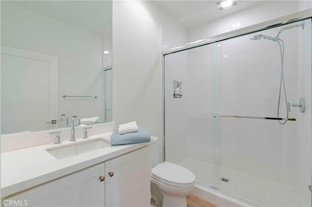 bathroom with a shower with door, toilet, and vanity