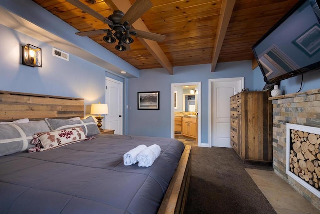 carpeted bedroom featuring ceiling fan, ensuite bathroom, beamed ceiling, and wood ceiling