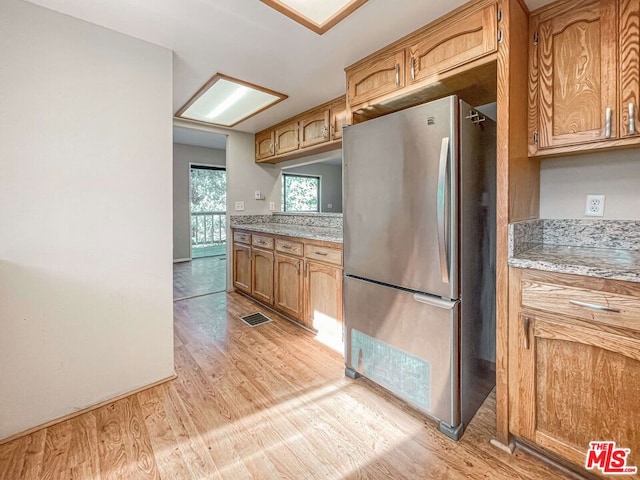 kitchen with light wood-type flooring and stainless steel fridge