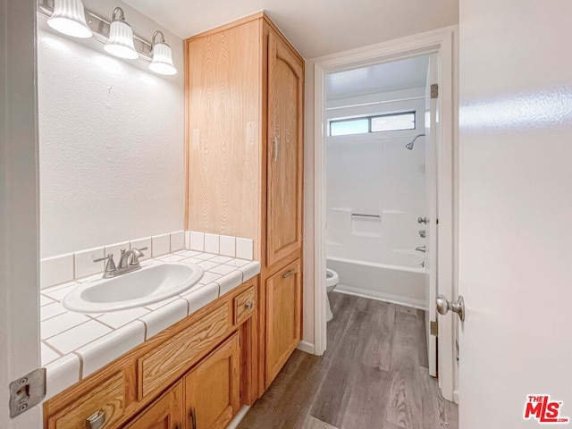 full bathroom featuring shower / bath combination, hardwood / wood-style floors, toilet, and vanity