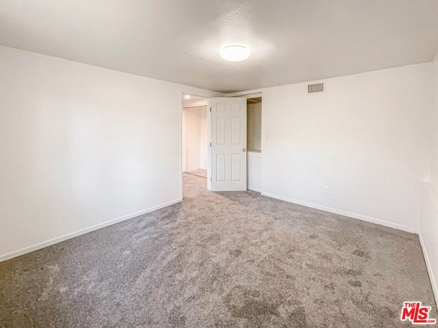 spare room featuring a textured ceiling and carpet flooring