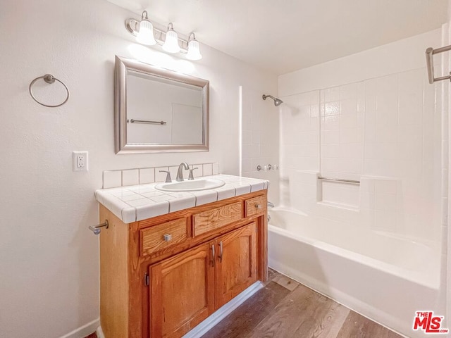 bathroom featuring hardwood / wood-style floors, washtub / shower combination, and vanity