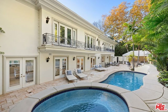 view of pool featuring a jacuzzi, french doors, and a patio