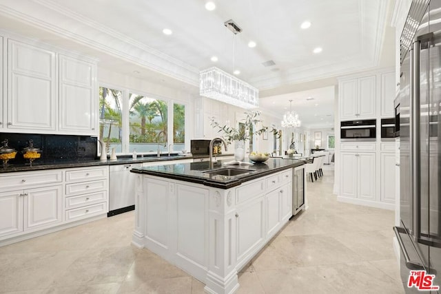 kitchen featuring white cabinetry, stainless steel appliances, a kitchen island with sink, pendant lighting, and sink