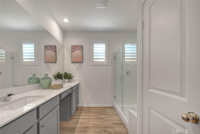 bathroom with wood-type flooring, walk in shower, and vanity