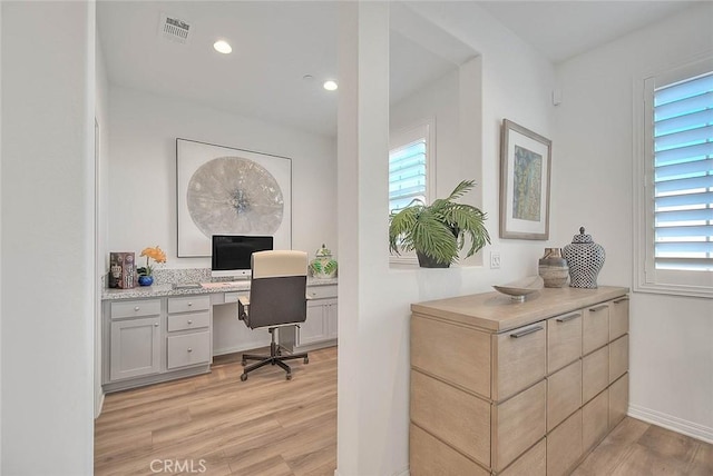 office with built in desk and light hardwood / wood-style floors