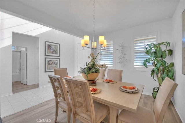 dining space with light hardwood / wood-style floors and a chandelier