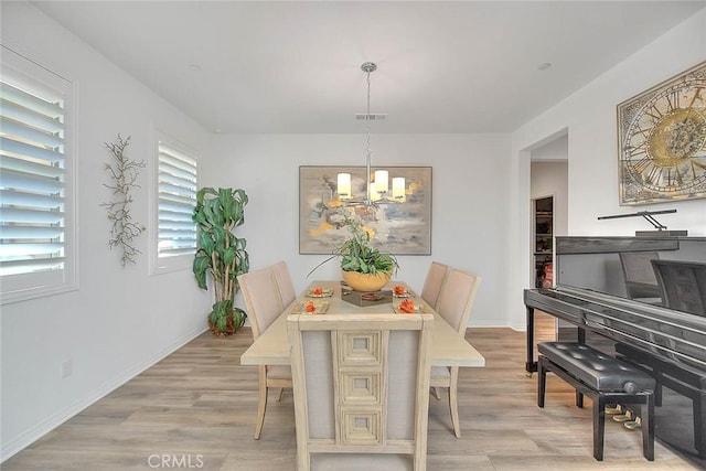 dining space featuring a notable chandelier and light wood-type flooring