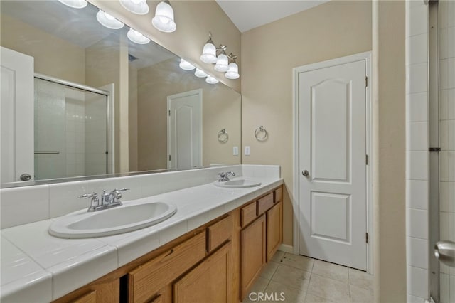 bathroom with a shower with shower door, vanity, and tile patterned flooring