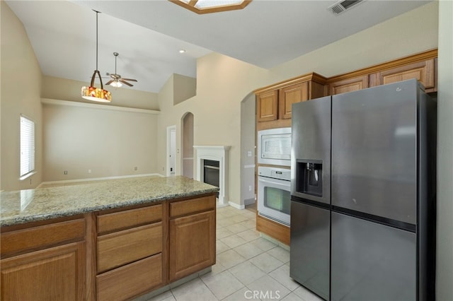 kitchen with ceiling fan, white appliances, light tile patterned flooring, light stone countertops, and vaulted ceiling