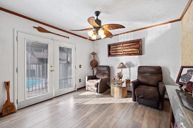 living area with ornamental molding, ceiling fan, light hardwood / wood-style floors, a textured ceiling, and french doors