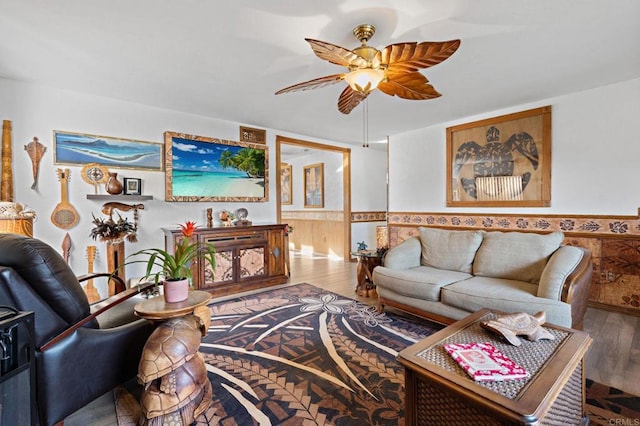 living room featuring a ceiling fan, wood finished floors, and wainscoting