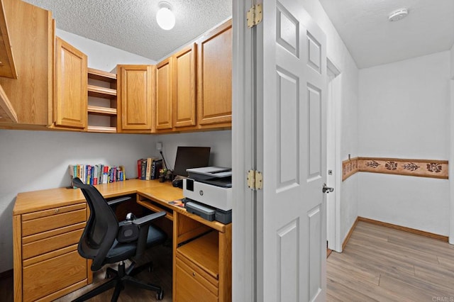 office area featuring lofted ceiling, light wood-style flooring, and a textured ceiling