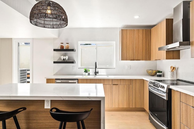 kitchen with electric stove, wall chimney exhaust hood, light hardwood / wood-style flooring, a breakfast bar, and sink