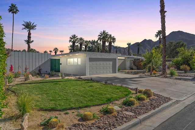 view of front facade featuring a mountain view, a yard, and a garage