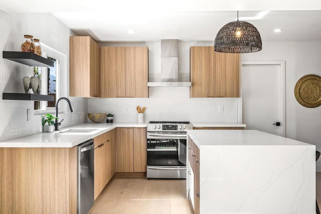 kitchen with appliances with stainless steel finishes, decorative light fixtures, light wood-type flooring, wall chimney range hood, and sink