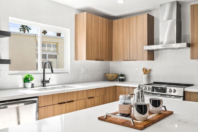 kitchen featuring tasteful backsplash, wall chimney range hood, sink, light stone countertops, and stainless steel appliances