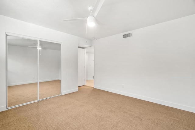 unfurnished bedroom featuring ceiling fan, a closet, and light colored carpet