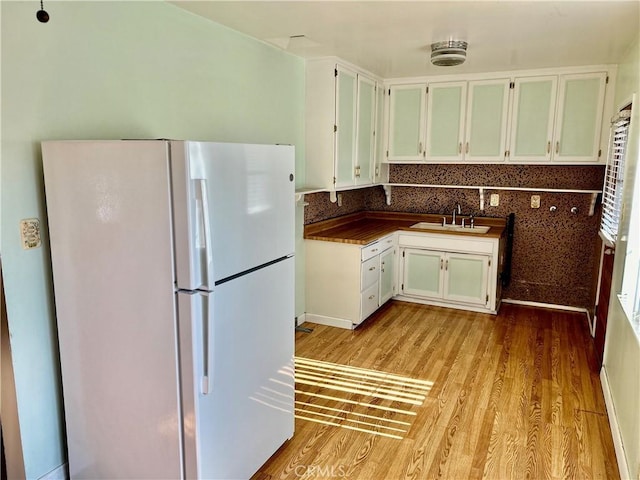 kitchen with light hardwood / wood-style floors, sink, white cabinetry, and white fridge